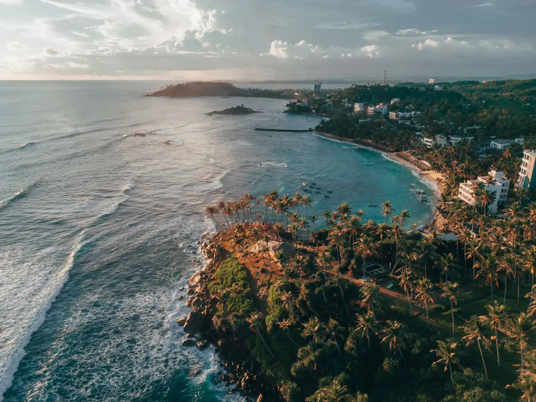 Sri Lanka's south coast — cliffs, breaking waves and palms at dusk.