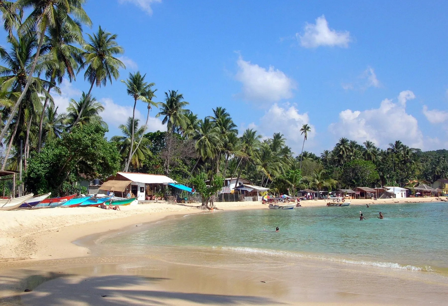 Palms, beach huts and boats along Unawatuna's curved bay.