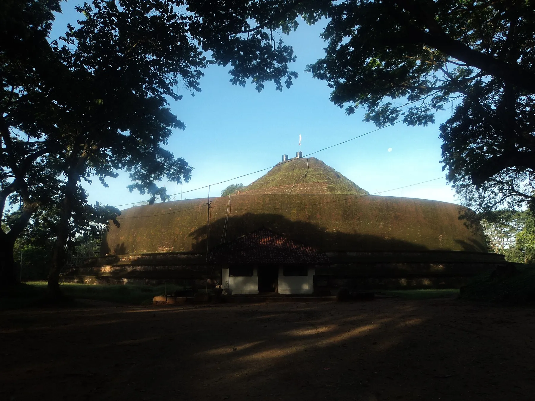 The large grass-covered dome of the ancient Yudaganawa stupa near Buttala under a blue sky.