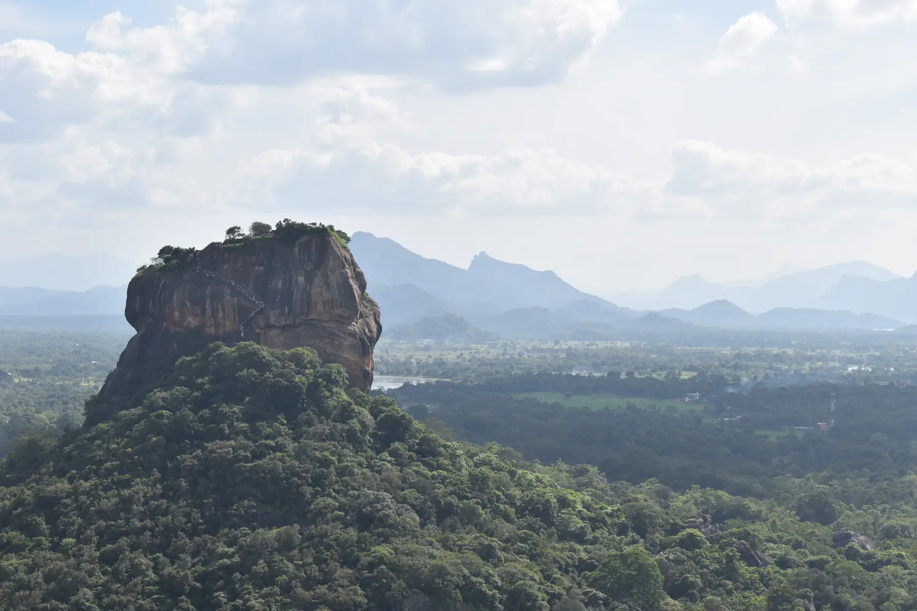 Sigiriya Rock seen from Pidurangala, with forest and distant hills.