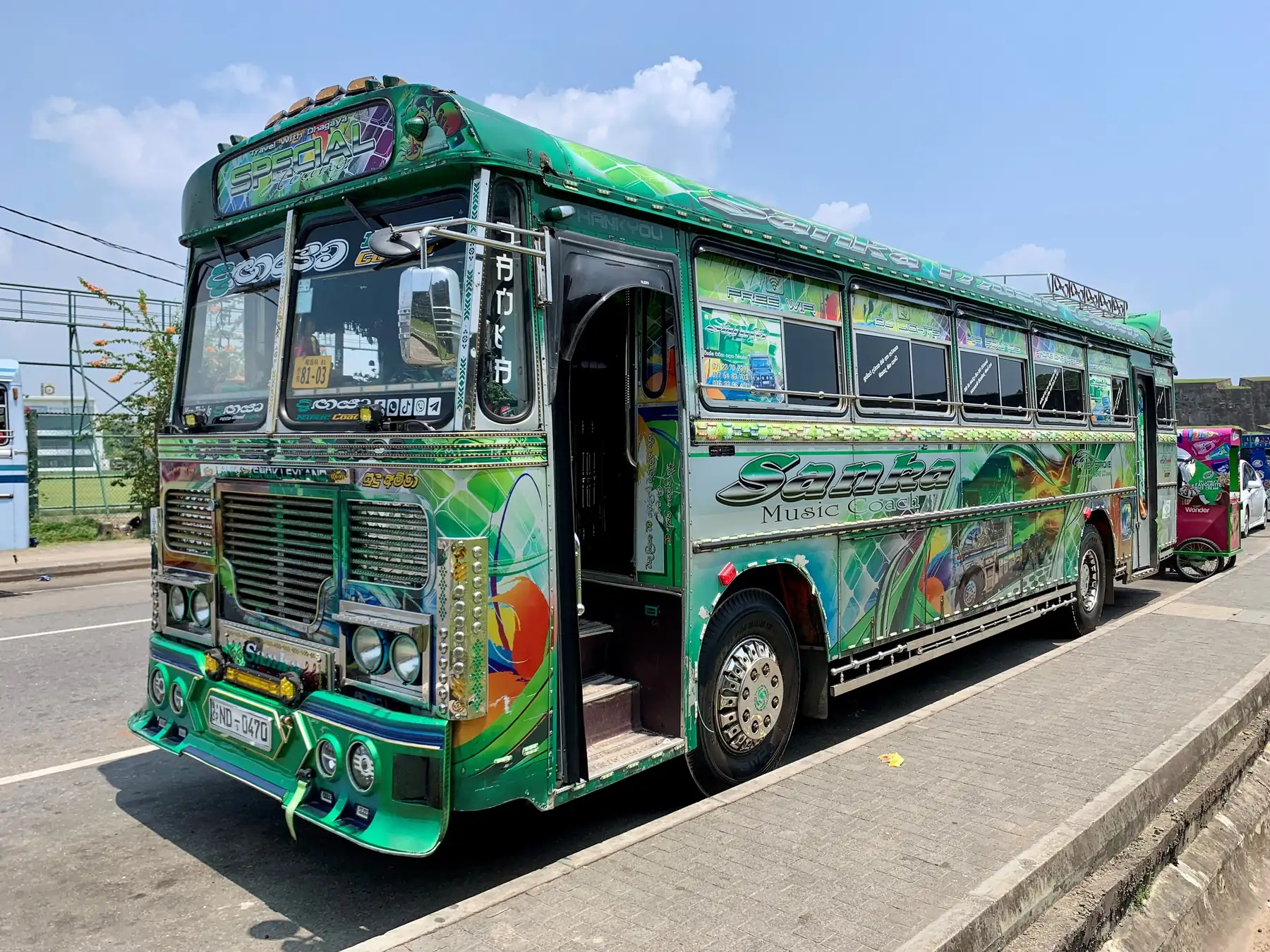 A brightly painted green passenger bus with a glittering front grille parked at the roadside in Galle.